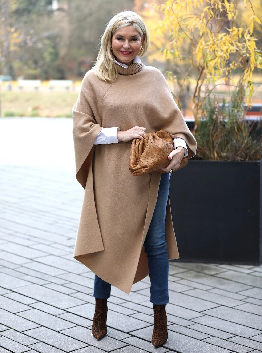 Woman wearing a beige poncho with jeans and ankle boots