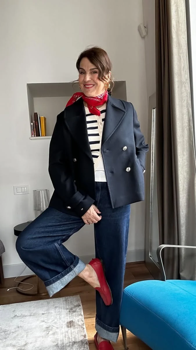 Woman wearing a navy peacoat with a red scarf, striped top and jeans