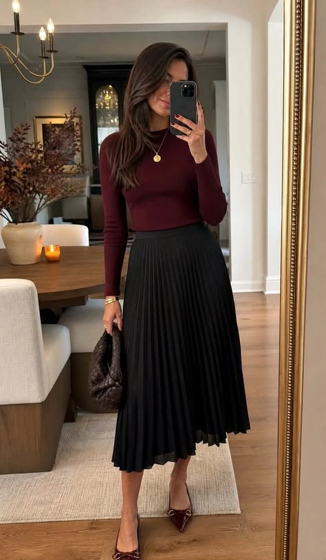 Wine colored knit top with black pleated midi skirt in a mirror selfie