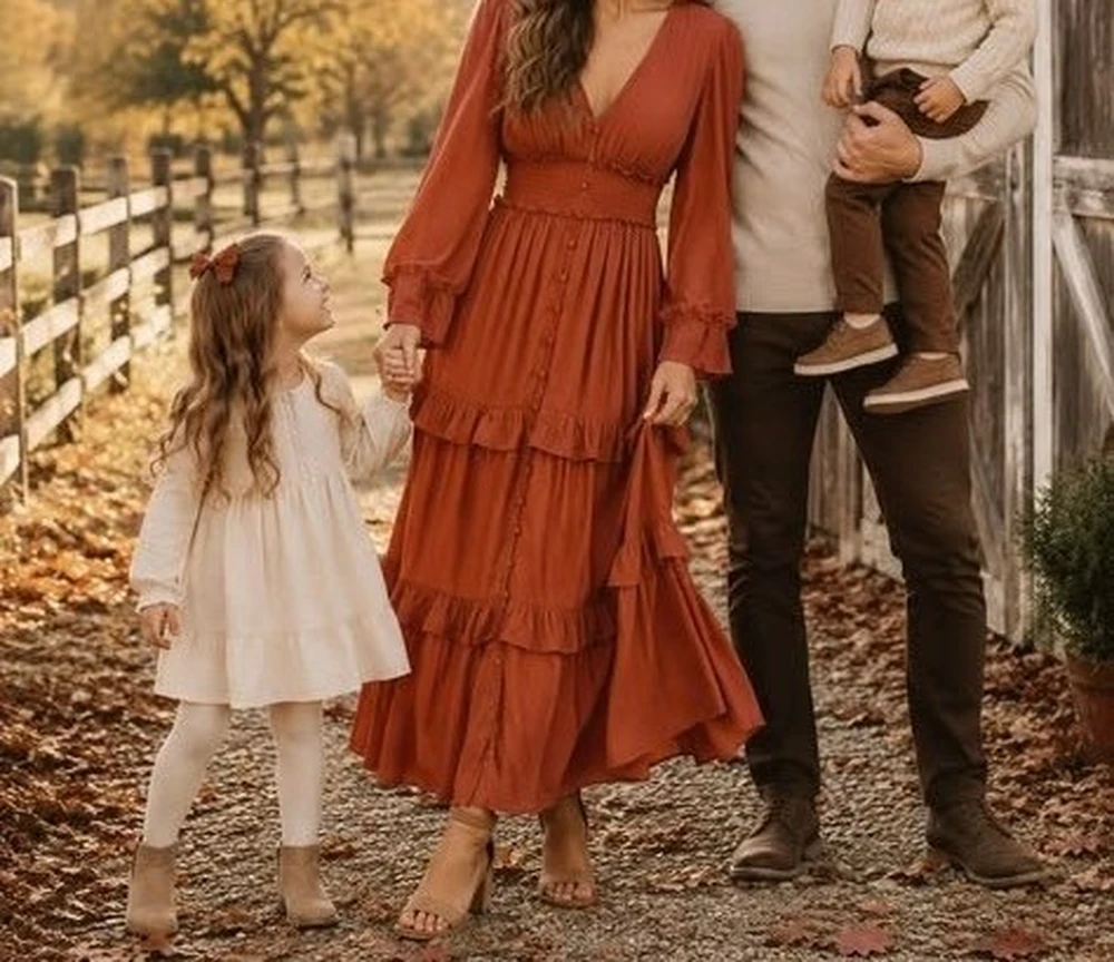 Family with mother in a rust tiered dress posing near a barn