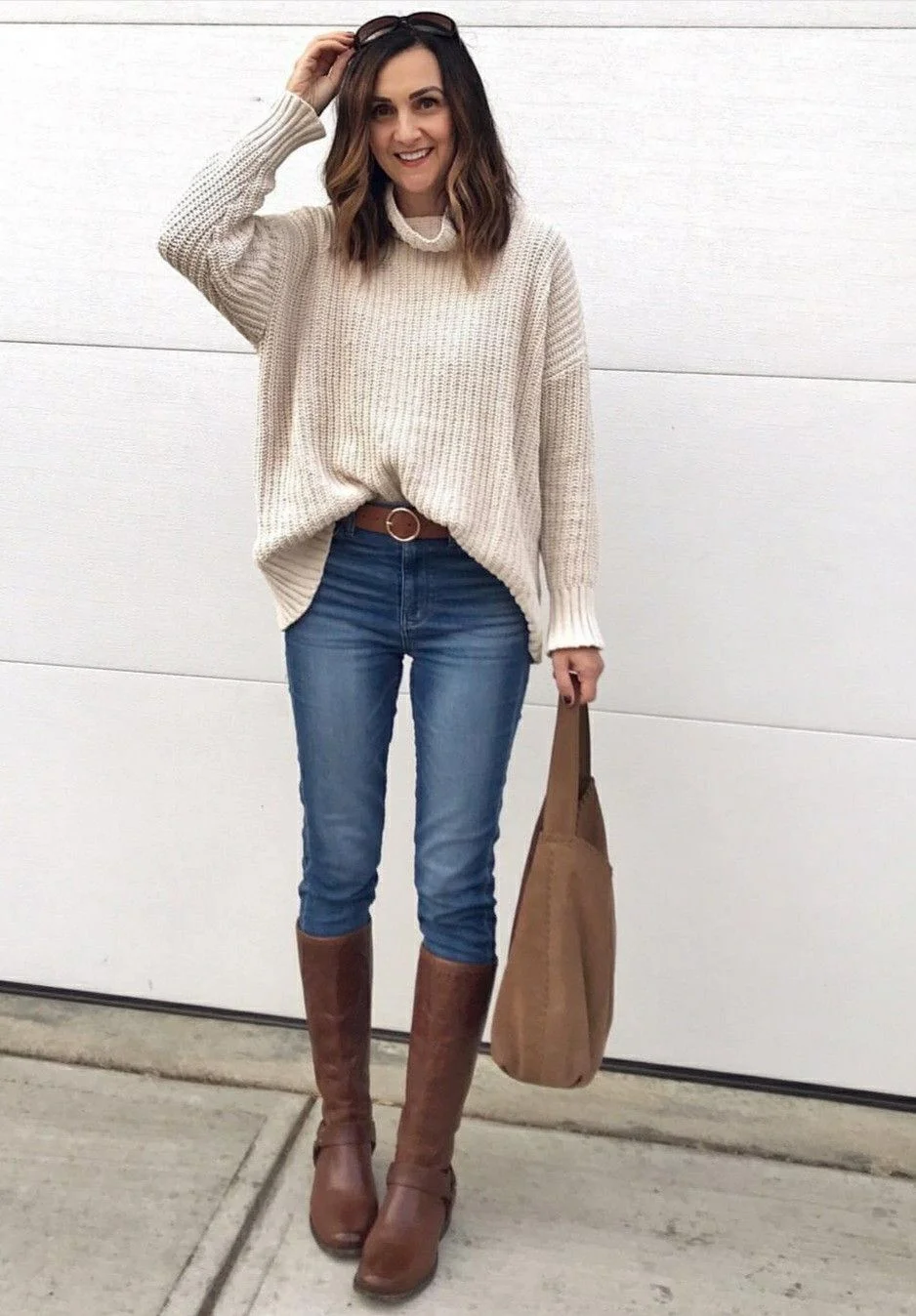Thanksgiving outfit with chunky knit sweater, medium jeans, and brown knee boots