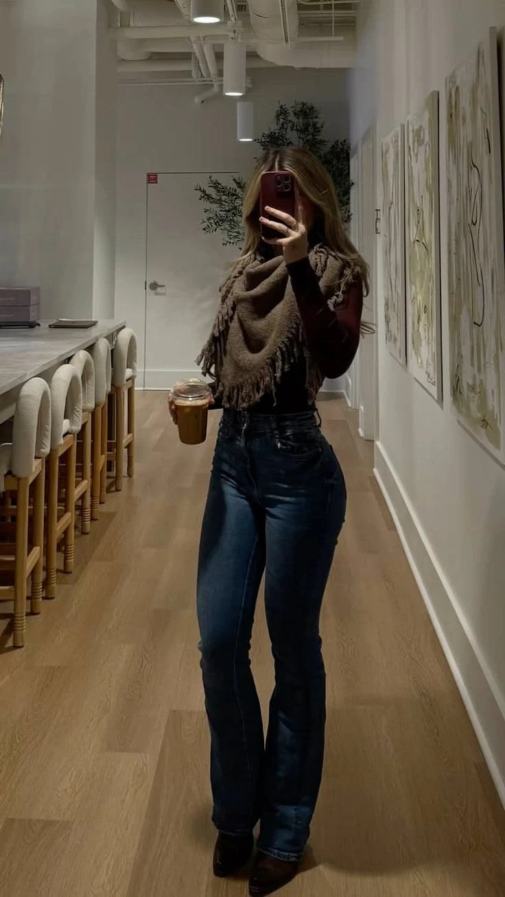 Thanksgiving outfit with dark flared jeans, pointed boots, and fringed scarf