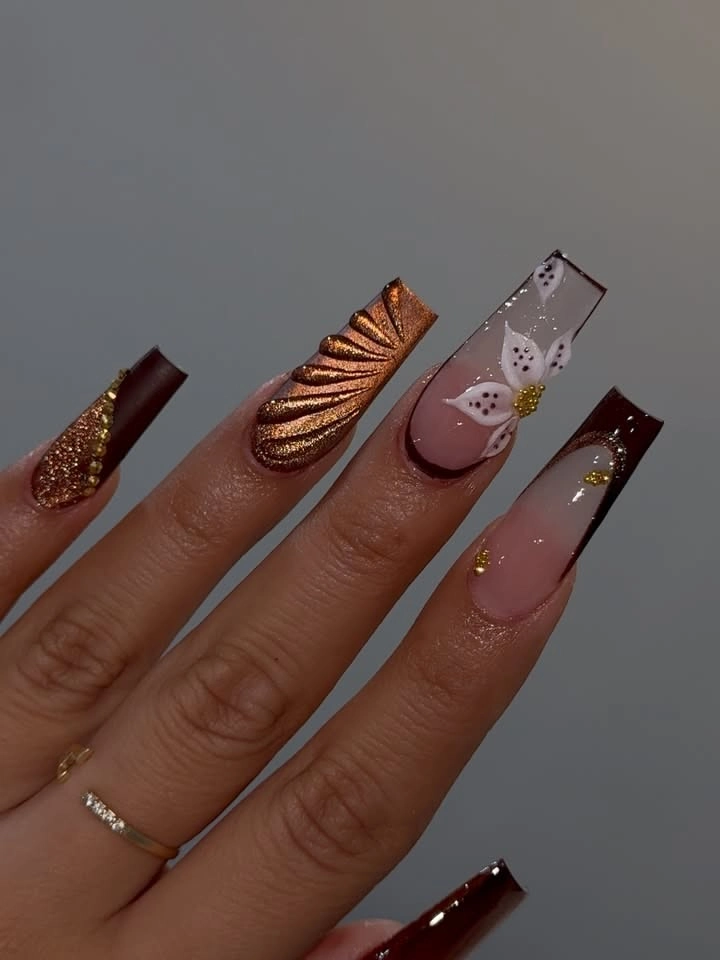 Long burgundy nails with copper shimmer and a white flower accent