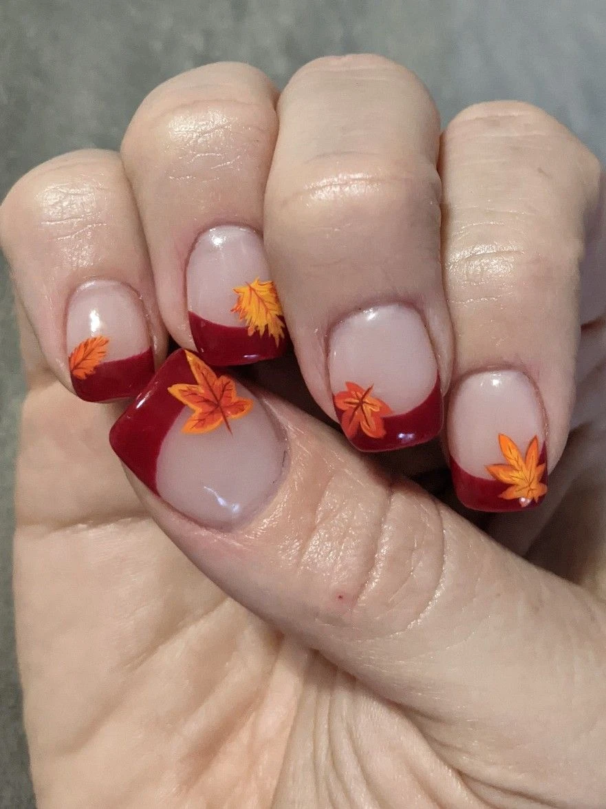 Red French tip nails with small orange maple leaves