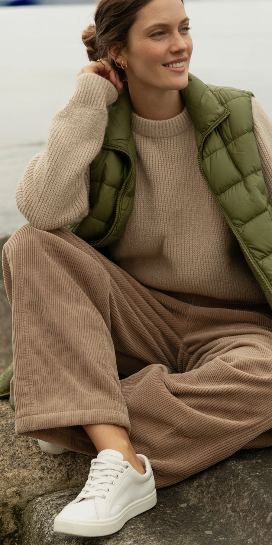 Woman wearing a puffer vest over a long sleeve top with corduroy pants
