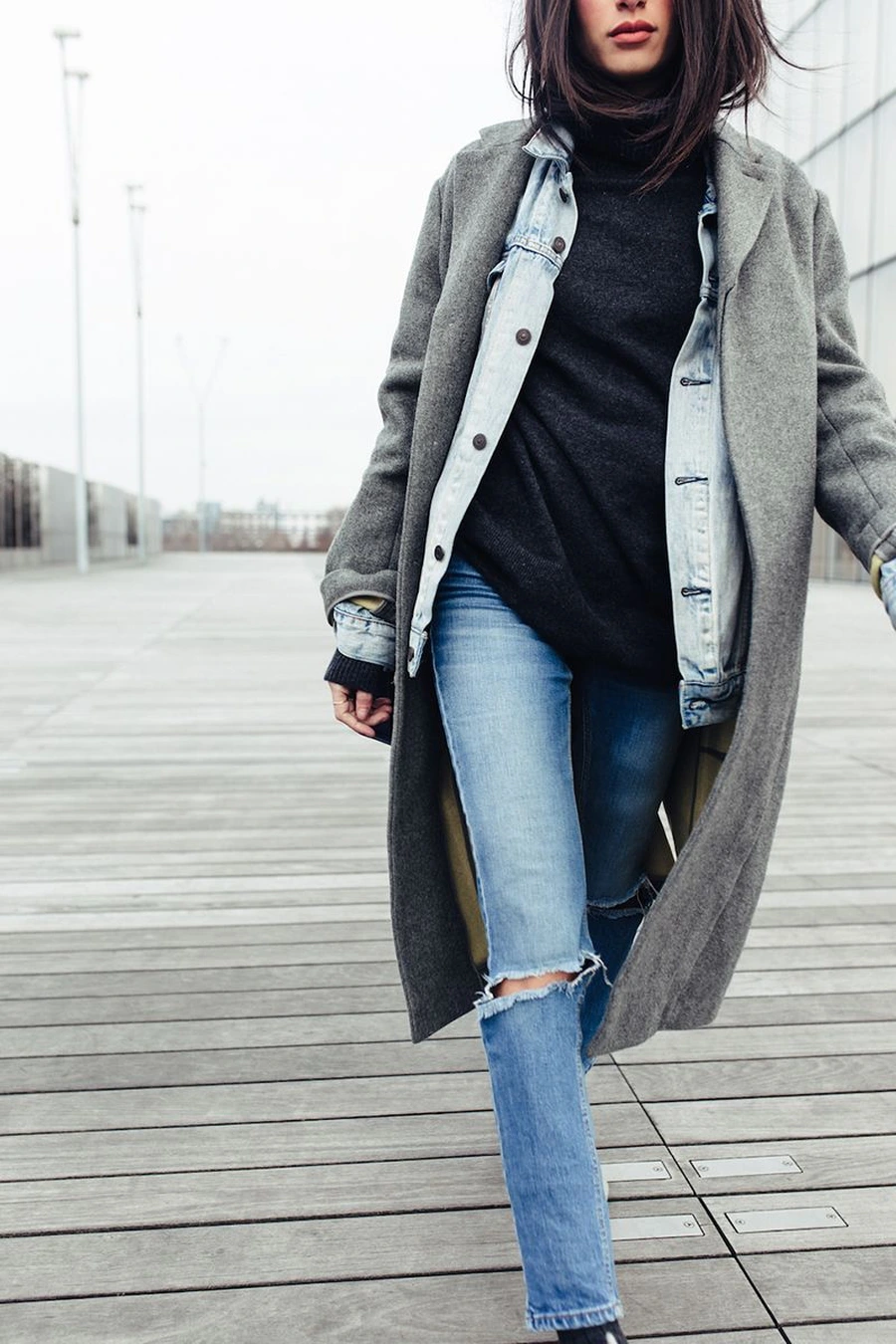 Woman layering a denim jacket under a wool coat