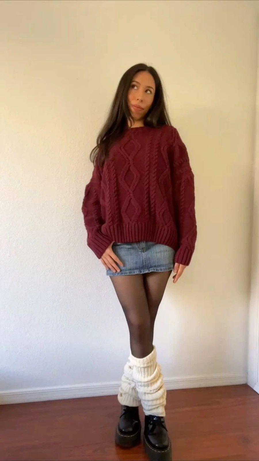 Woman in a cable knit sweater with a denim skirt and tights