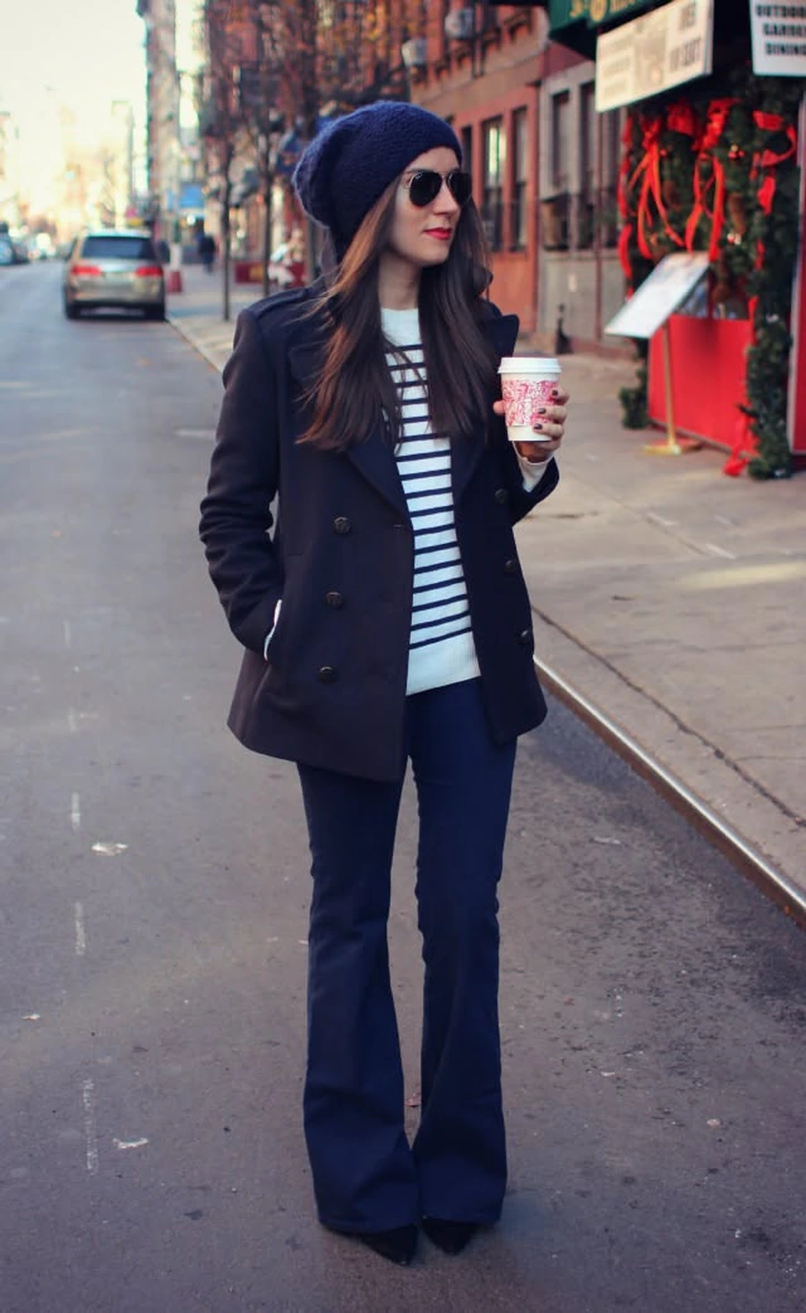 Woman in a pea coat with a striped sweater and dark jeans
