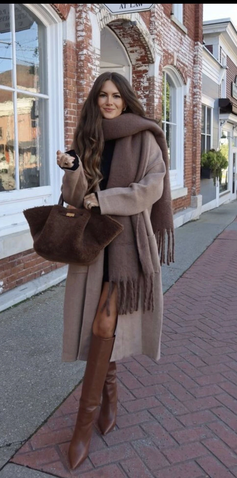 Woman in a chunky knit scarf and coat over a sweater dress