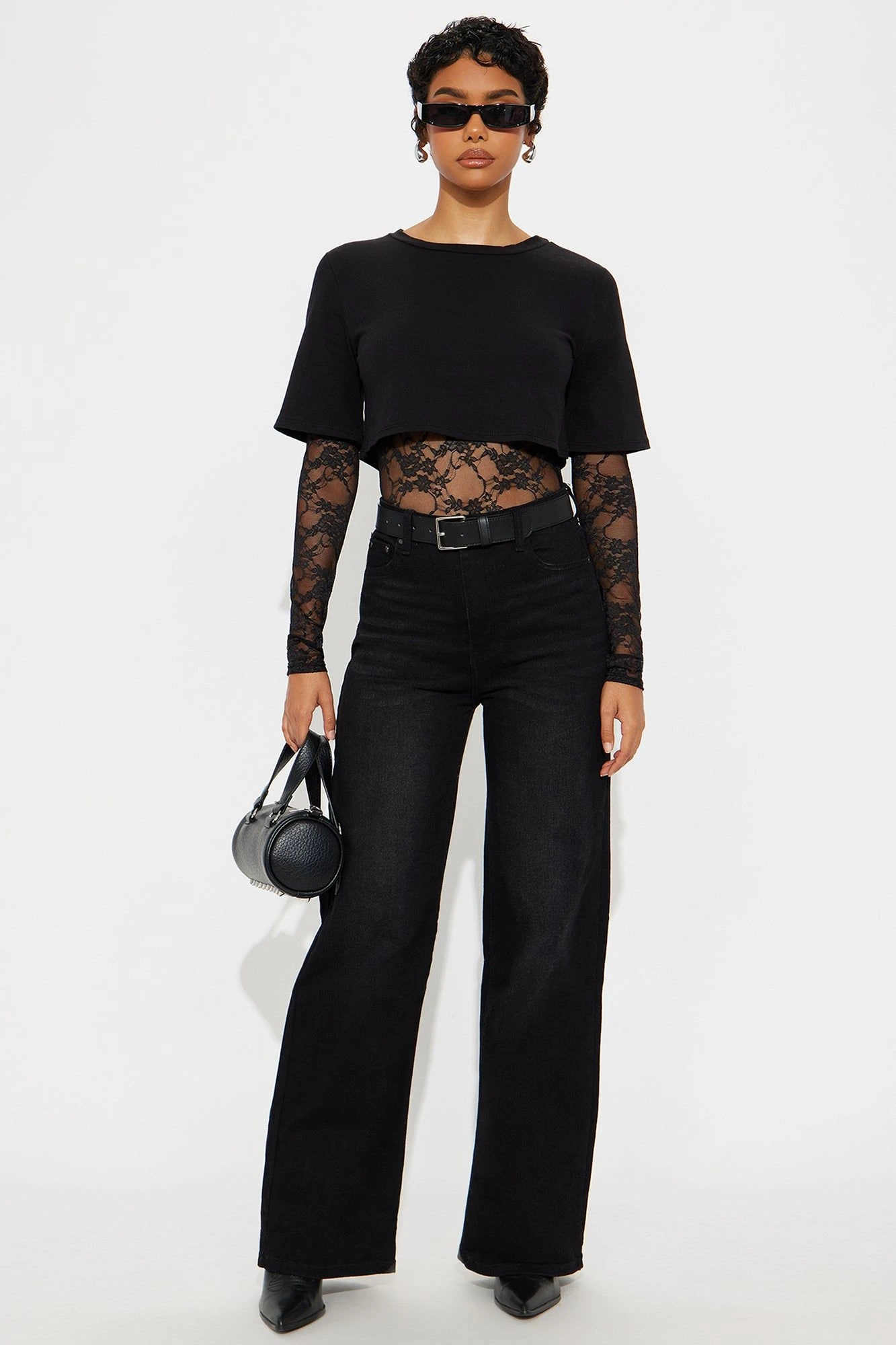 Woman in a black lace top with dark jeans and leather boots