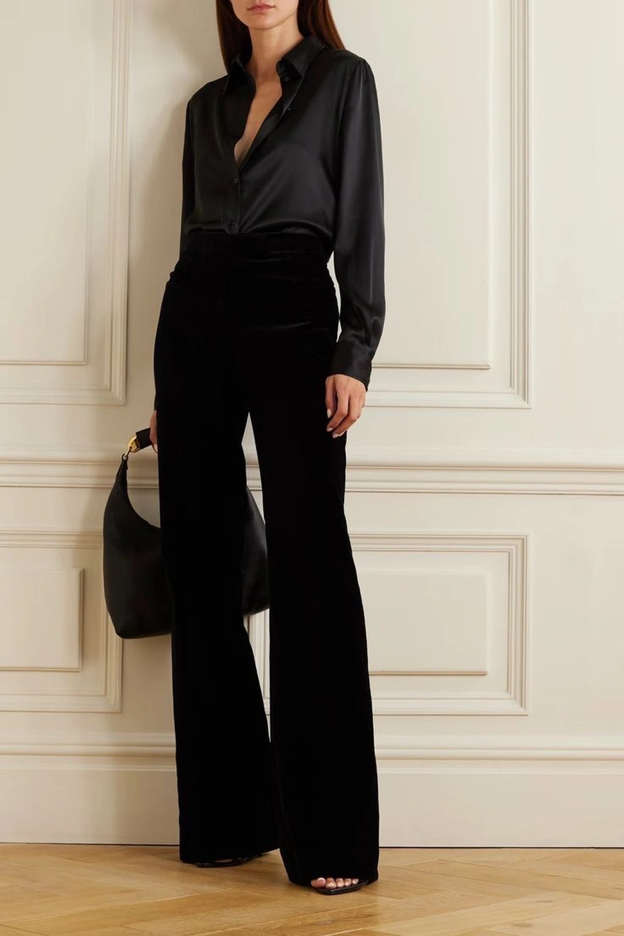 Woman in a black satin blouse with velvet trousers and heels