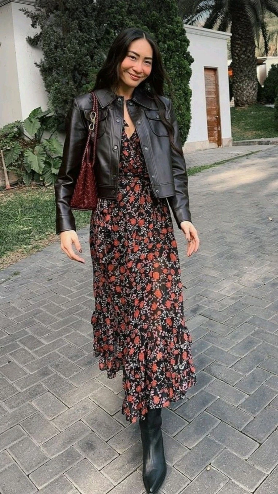 Woman wearing a dark floral midi dress with a black cardigan and boots