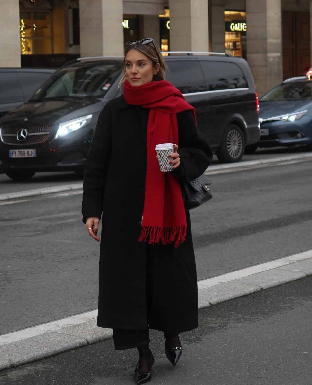 Woman in a deep red coat with a black scarf and tailored pants