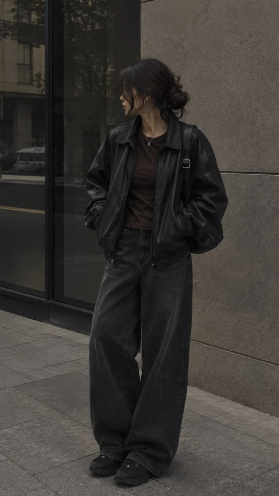 Woman wearing a black leather jacket with a dark knit and black jeans