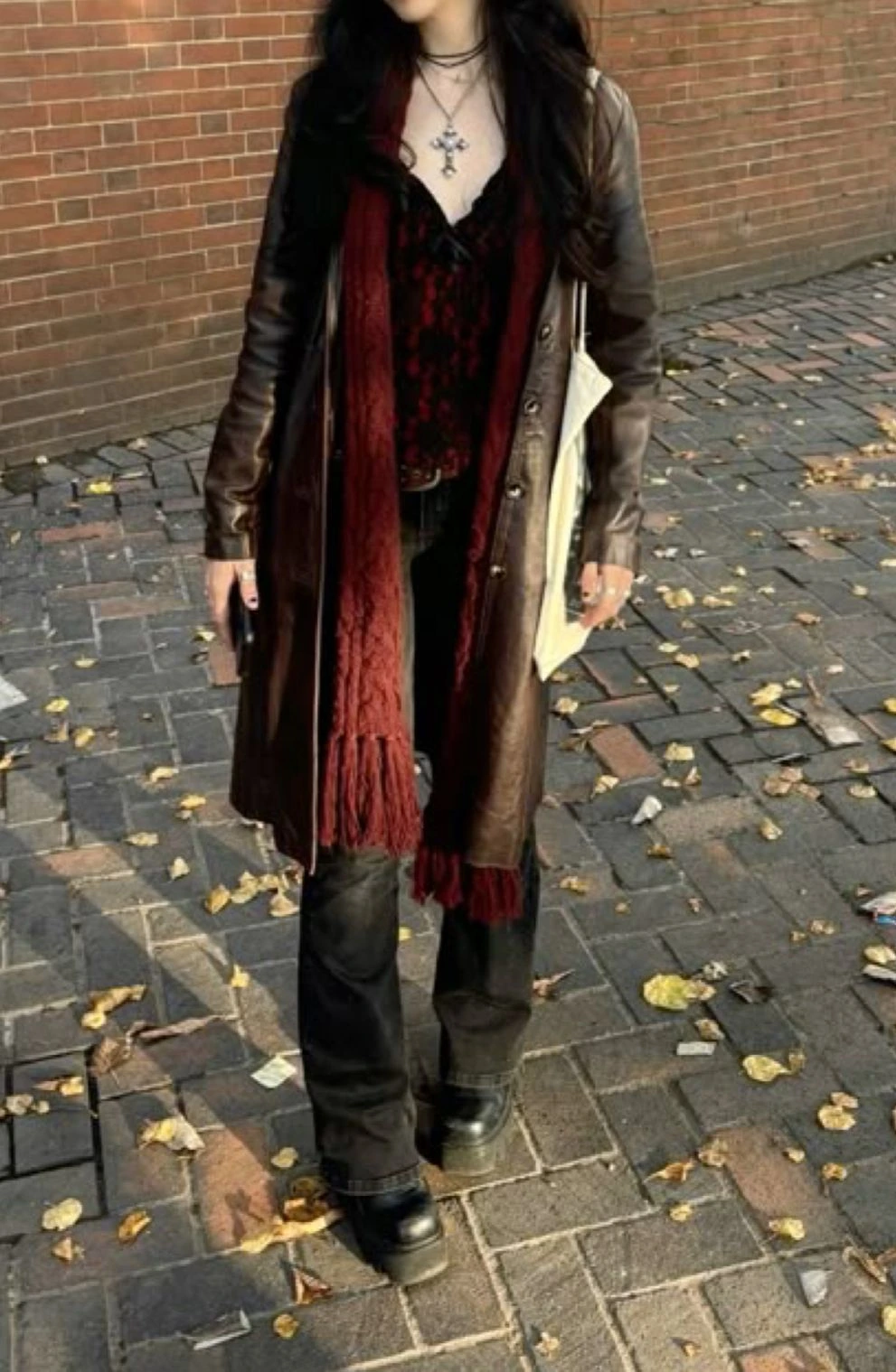 Woman wearing oxblood boots with a black coat and burgundy scarf