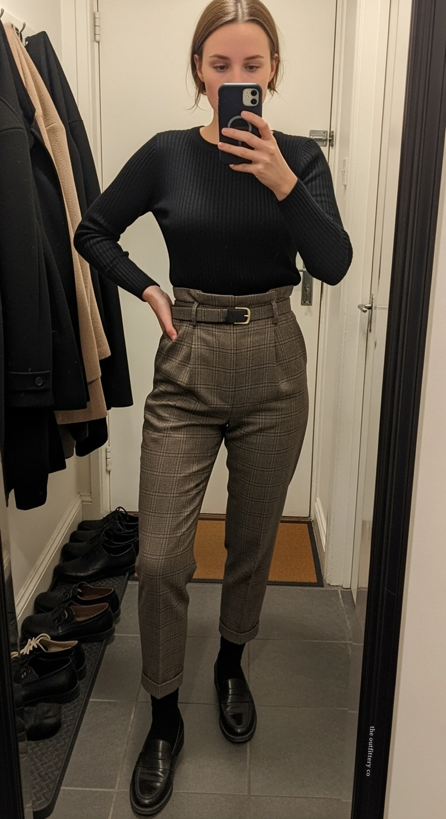 Woman in plaid trousers with a black knit and oxford shoes