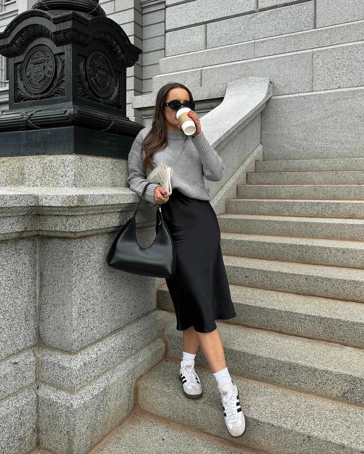 Woman wearing sneakers with a satin midi skirt and oversized sweater