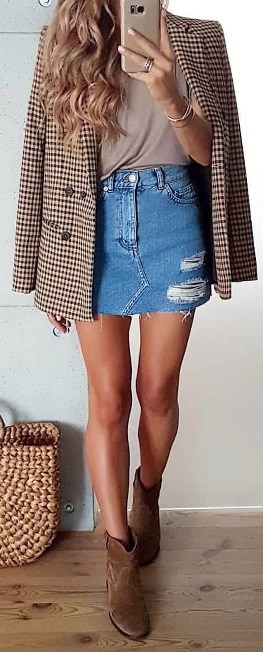 Woman in a double breasted blazer with a denim mini skirt and boots