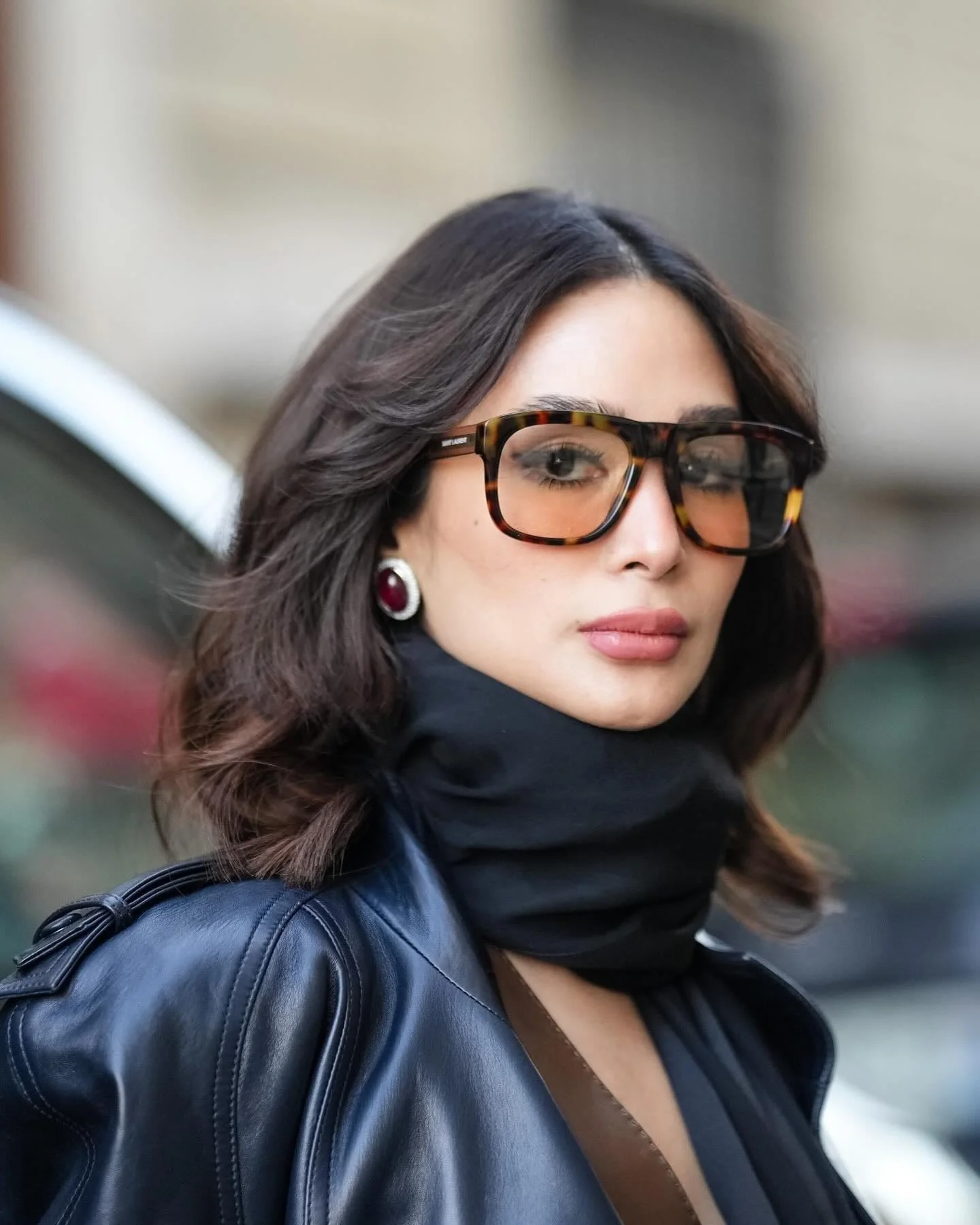 Black leather coat with black scarf and tortoise glasses, mob wife outfit