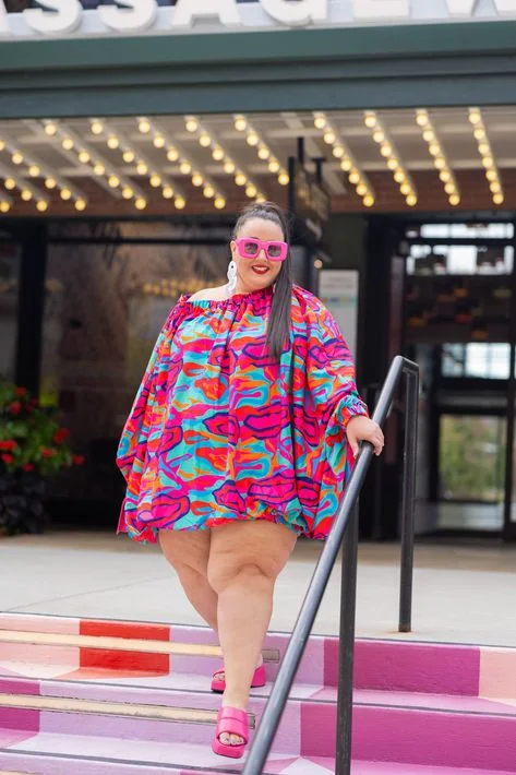 Neon abstract print off-shoulder dress with pink sunglasses on theater steps