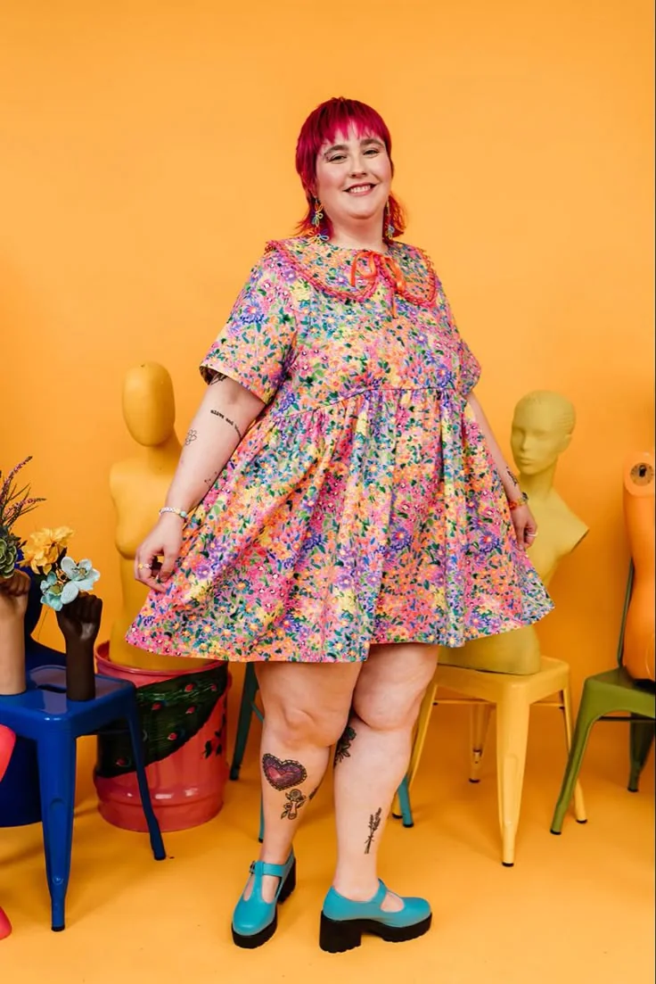 Confetti floral babydoll dress with turquoise Mary Janes in an orange studio