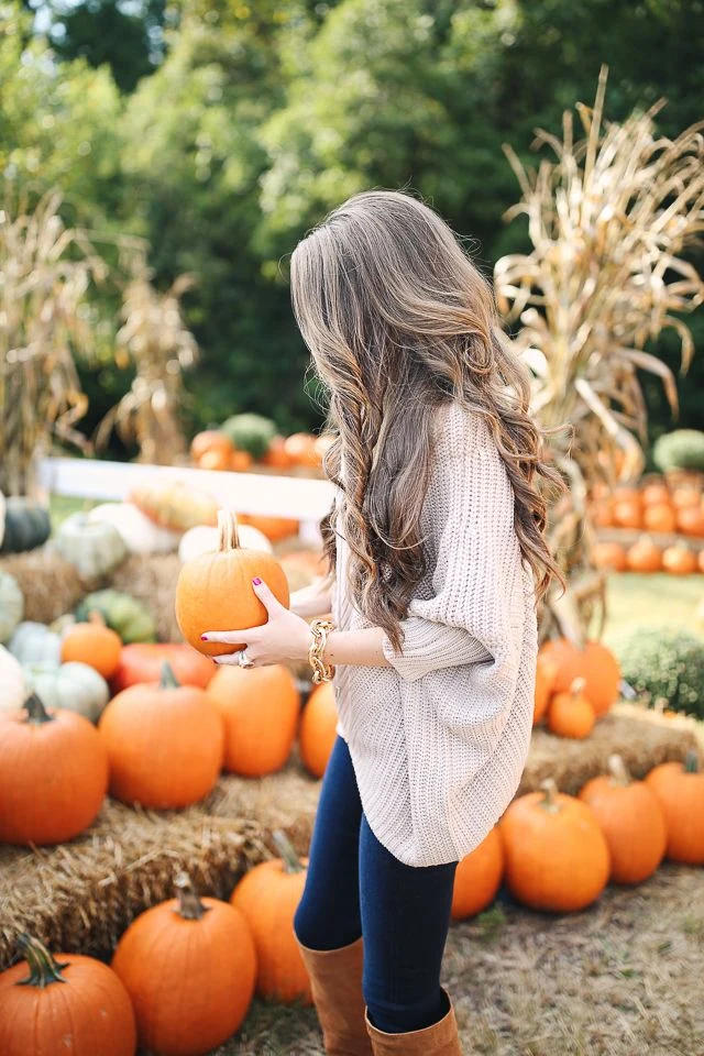 Plus size pumpkin patch outfit: knit poncho with dark jeans and tan boots