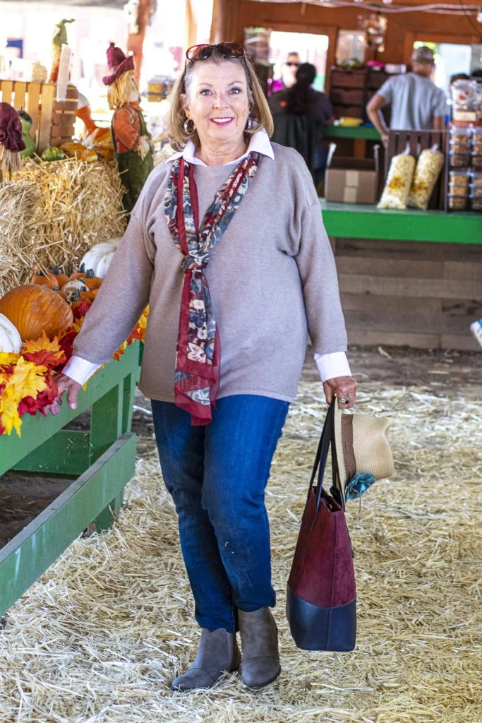 Plus size pumpkin patch outfit: taupe sweater with printed scarf and jeans