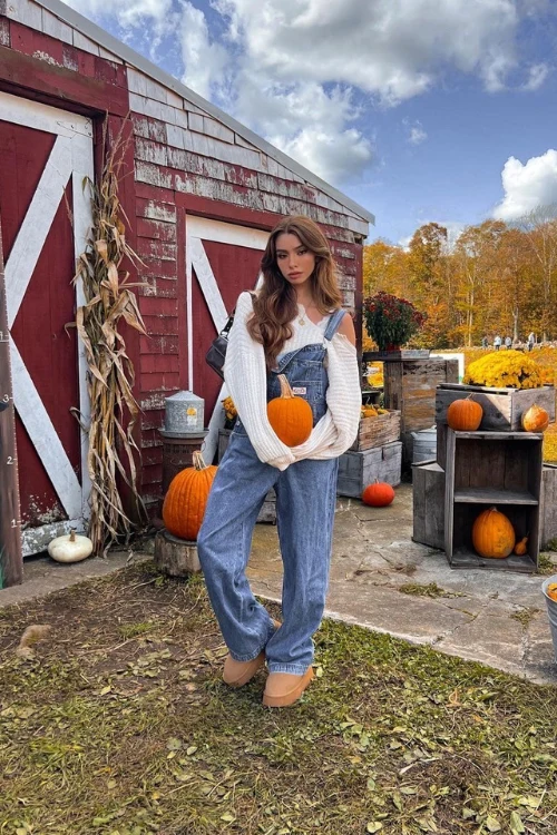 Fall pumpkin patch outfit: white off-shoulder sweater with denim overalls at a red barn