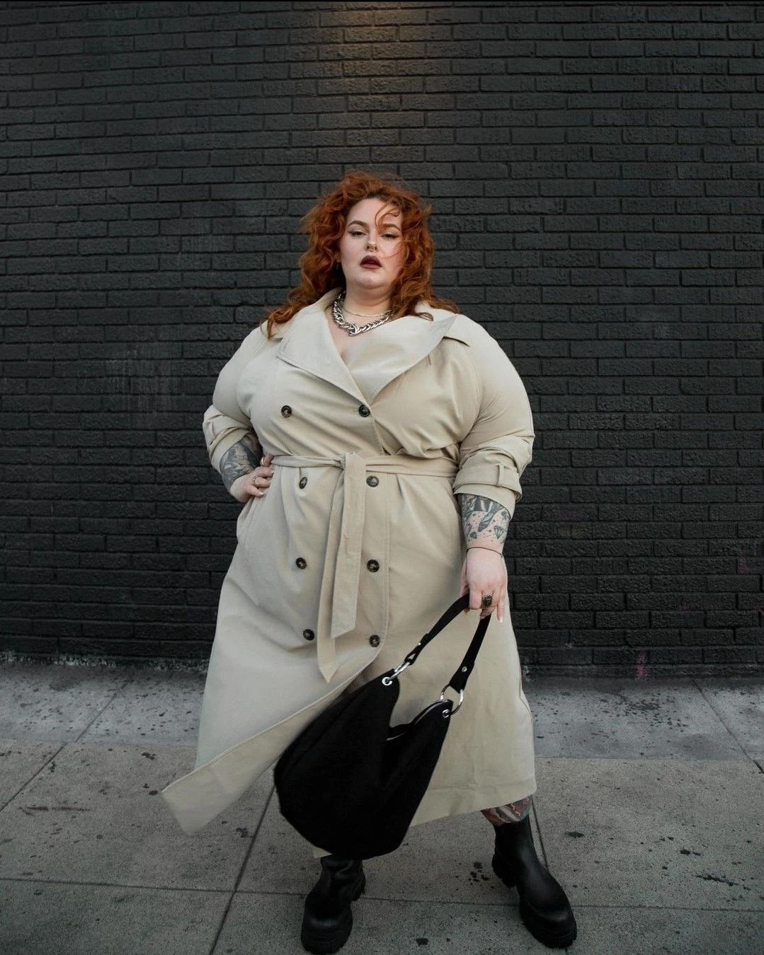 Plus-size woman in a cream trench coat with a black handbag, fall street style