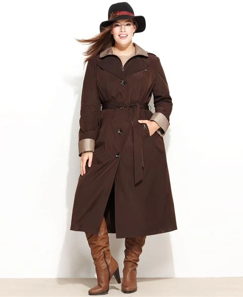 Plus-size woman in a belted dark brown raincoat, tall brown boots and a black hat
