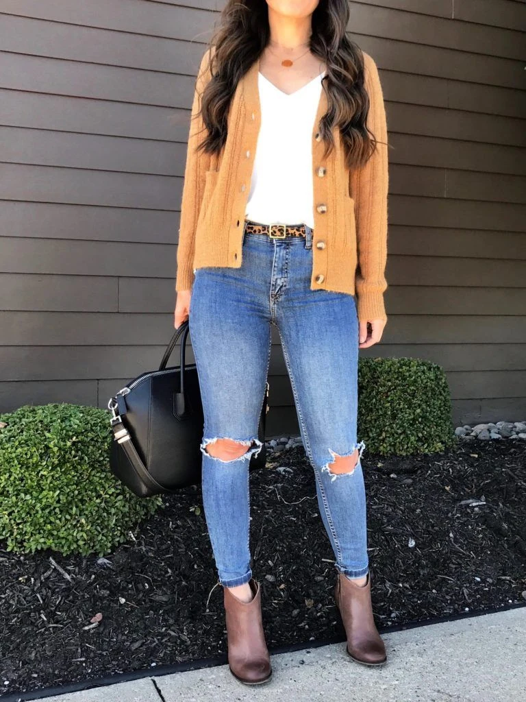 Petite woman wearing mustard cardigan with jeans and ankle boots for Thanksgiving