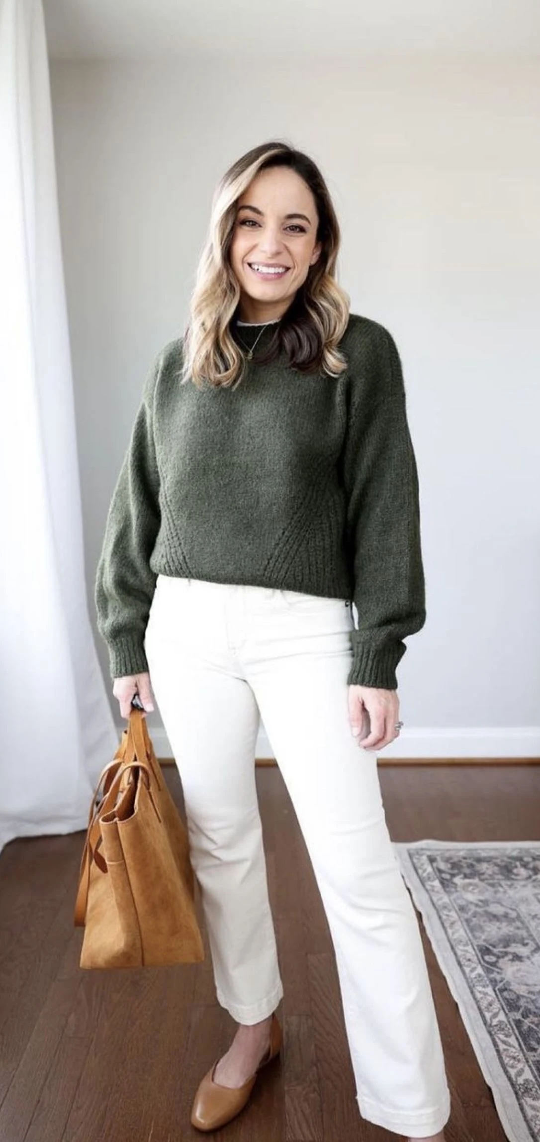 Petite woman wearing olive sweater with cream slim jeans for Thanksgiving