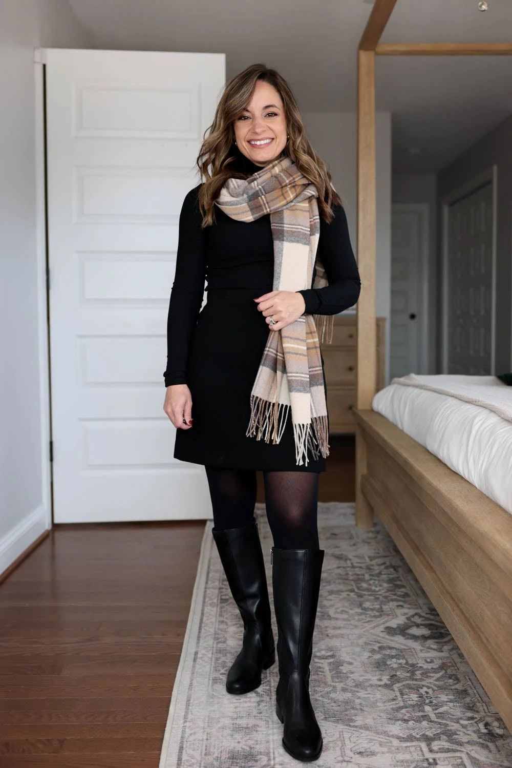 Petite fall outfit: A black long-sleeve knit dress with black tights, knee-high black boots and a beige plaid scarf.