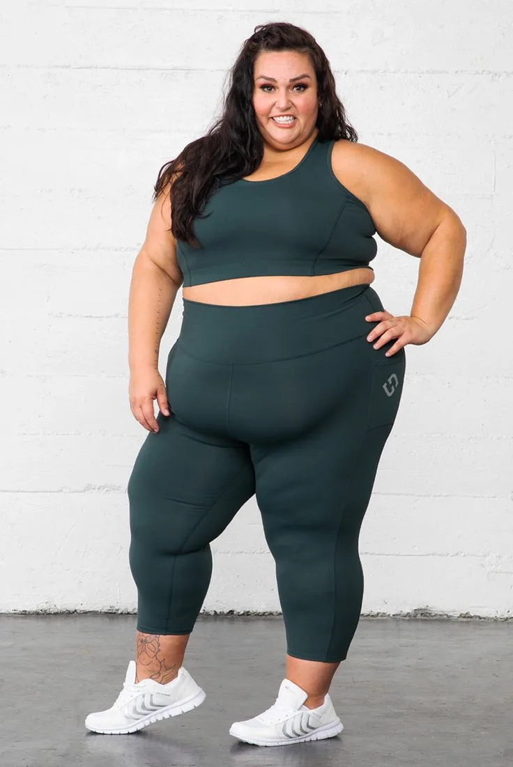 Plus size woman in dark green matching sports bra and leggings set