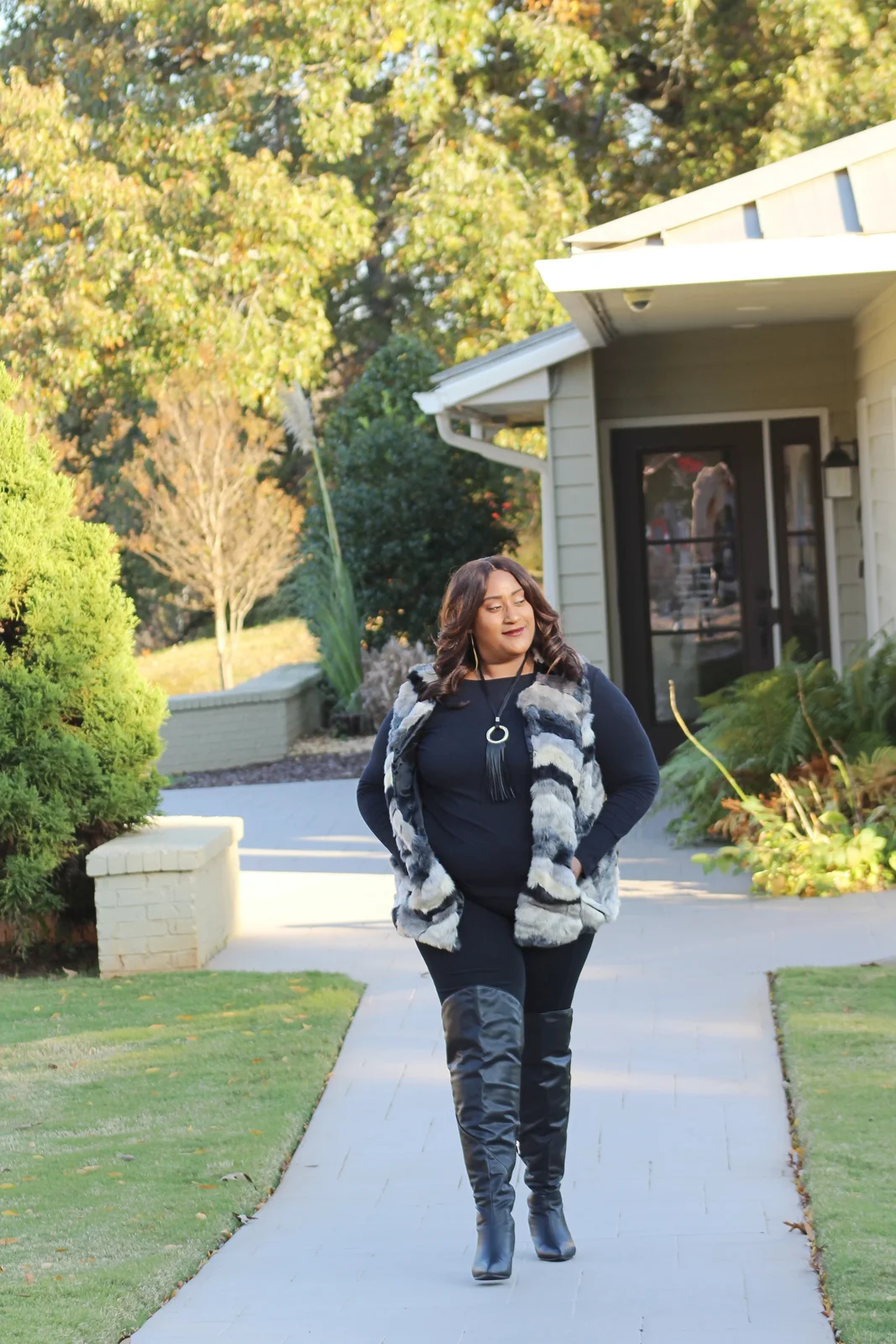 Fall outfit for black woman: black top with fur vest and over the knee boots