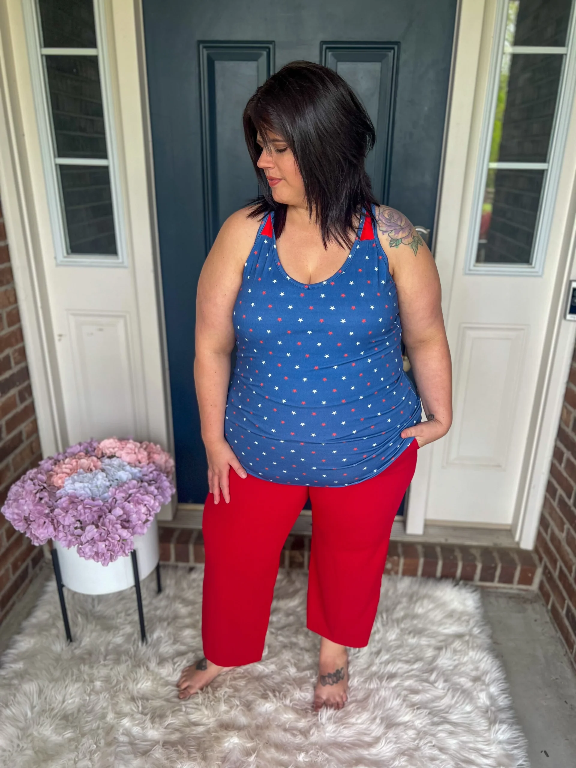 Plus size woman in blue star print tank top and red wide-leg pants