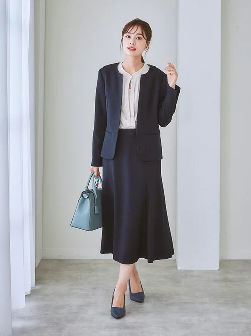 Veterans Day work outfit: Navy tailored jacket with white blouse and navy midi skirt and teal bag