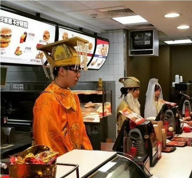 Woman in an orange imperial costume ordering at a fast food counter