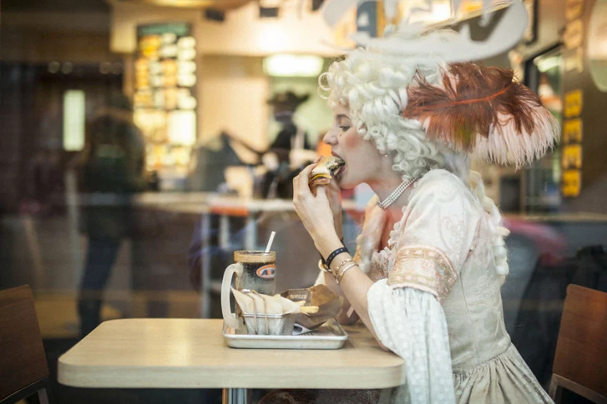 Woman in a white Victorian style dress eating at a fast food restaurant