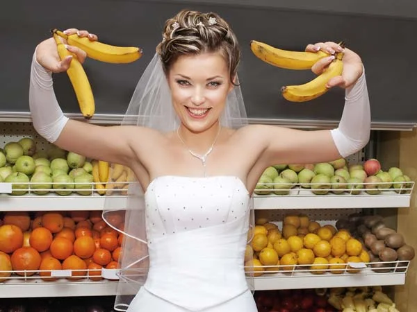 Bride holding up bananas like barbells in a grocery store
