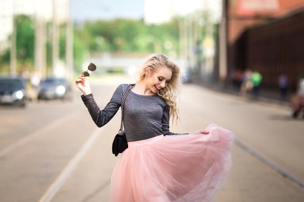 Woman in a pink tulle skirt twirling on a city street